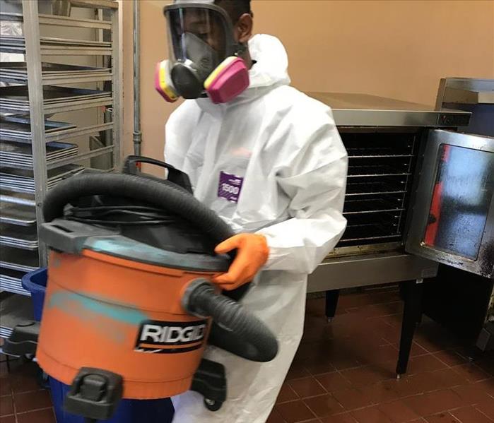 crew member in mold restoration hazmat suit carrying equipment
